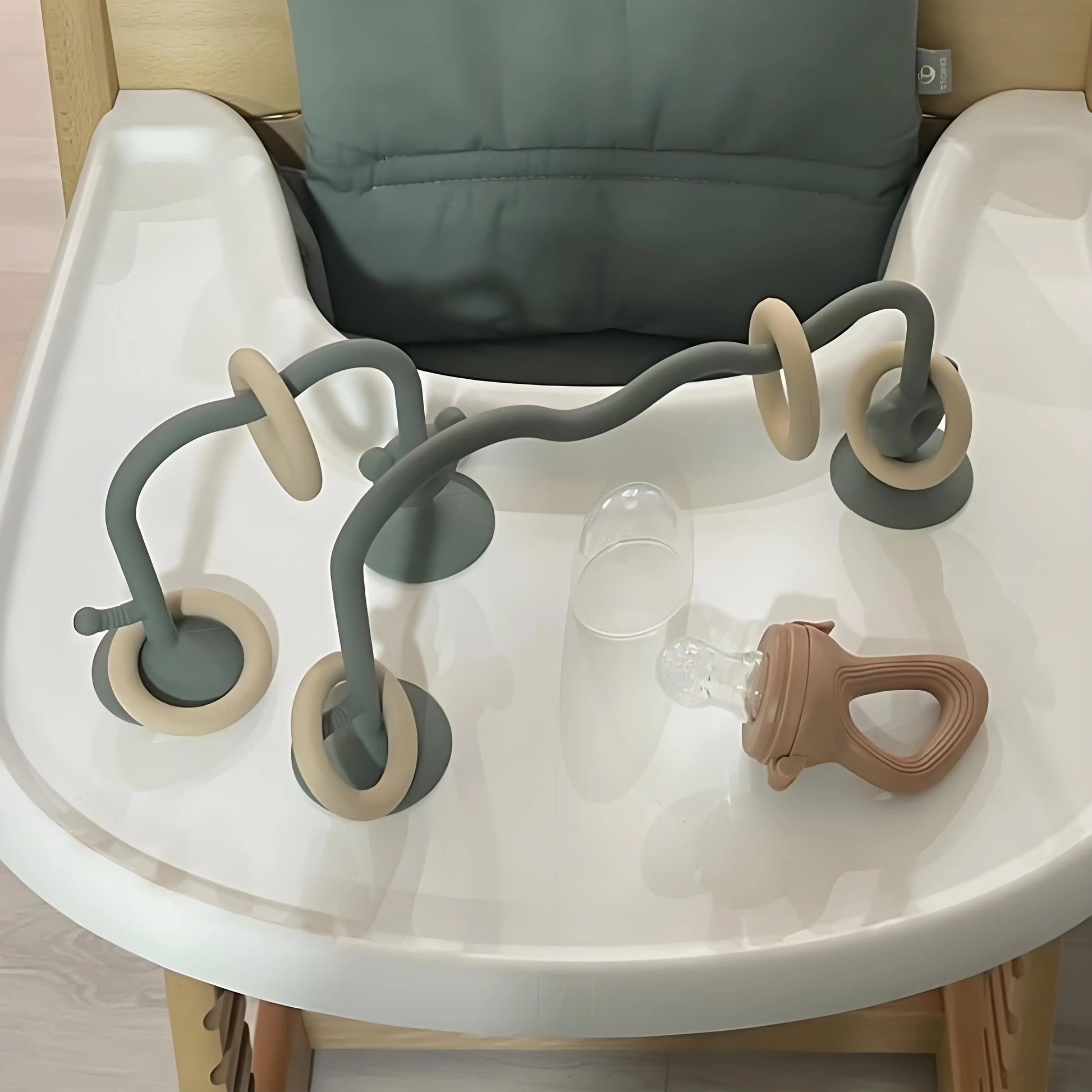 Silicone bead maze toy attached to baby feeding chair using suction cups.