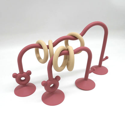 Reddish pink silicone bead maze toy for babies with suction cups and sliding rings.