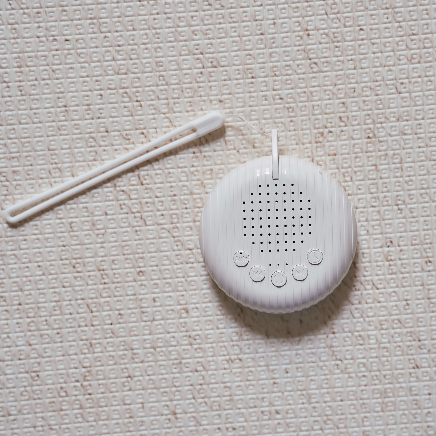 Compact white noise machine for babies placed on soft neutral fabric surface