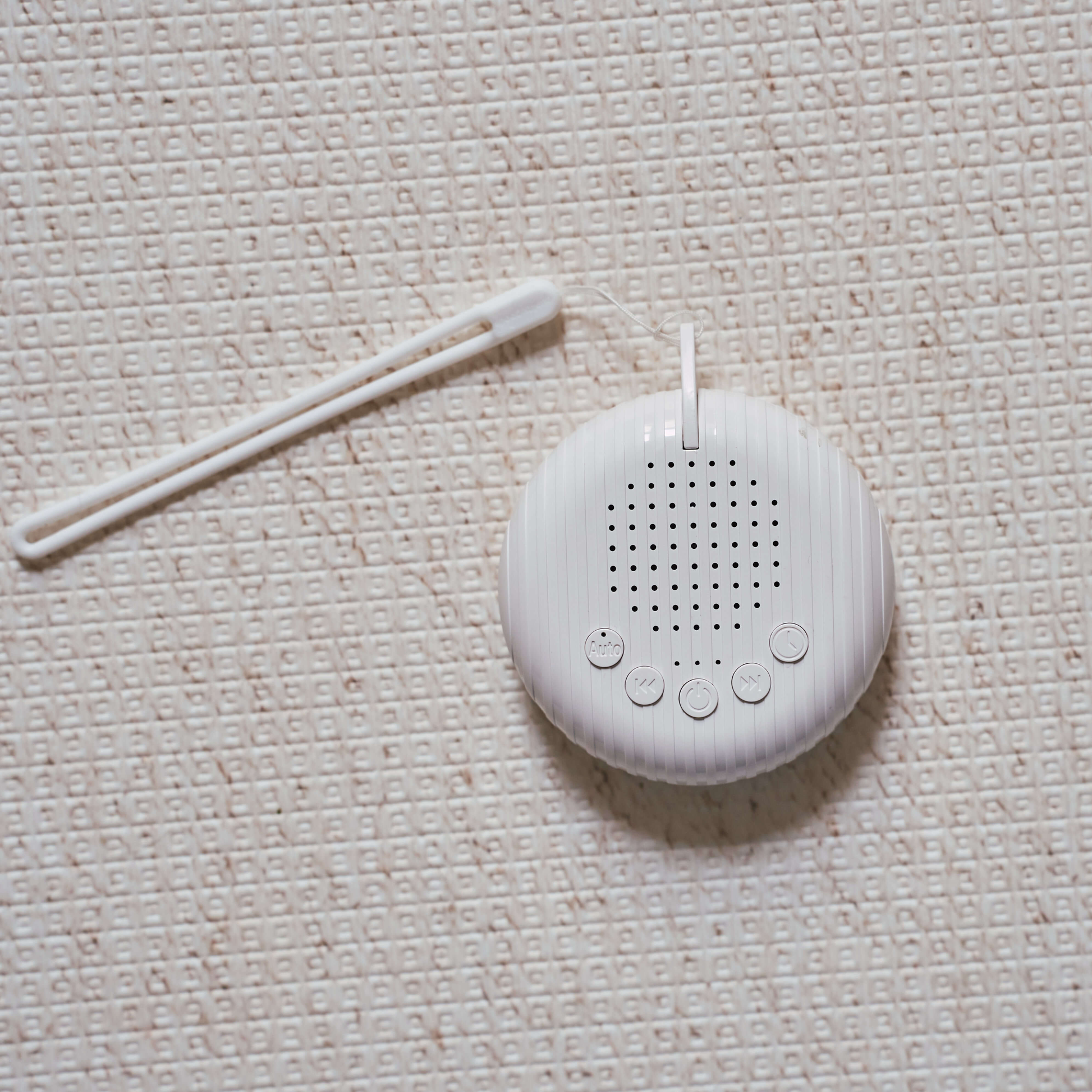 Compact white noise machine for babies placed on soft neutral fabric surface