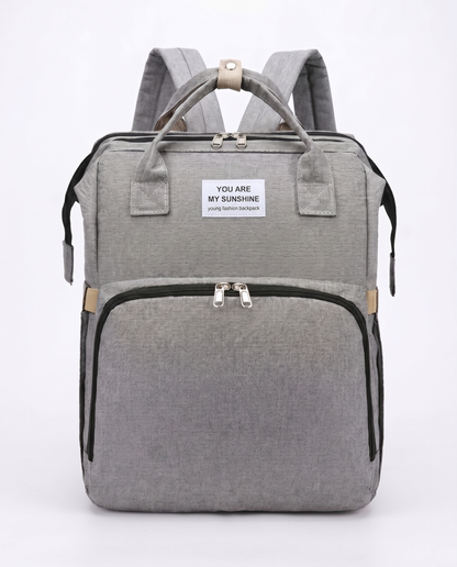 Grey foldable baby diaper backpack with carry handles, large front pocket and beige zip detail