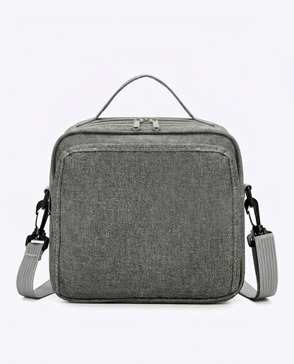 Compact grey nappy bag with dual zip closure and adjustable shoulder strap on white background