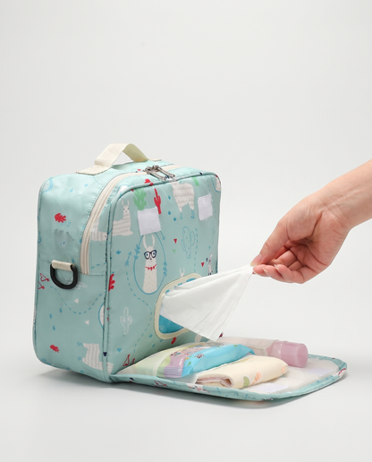 Nappy bag open on flat surface showing changing mat flap with nappies, wipes, and baby essentials