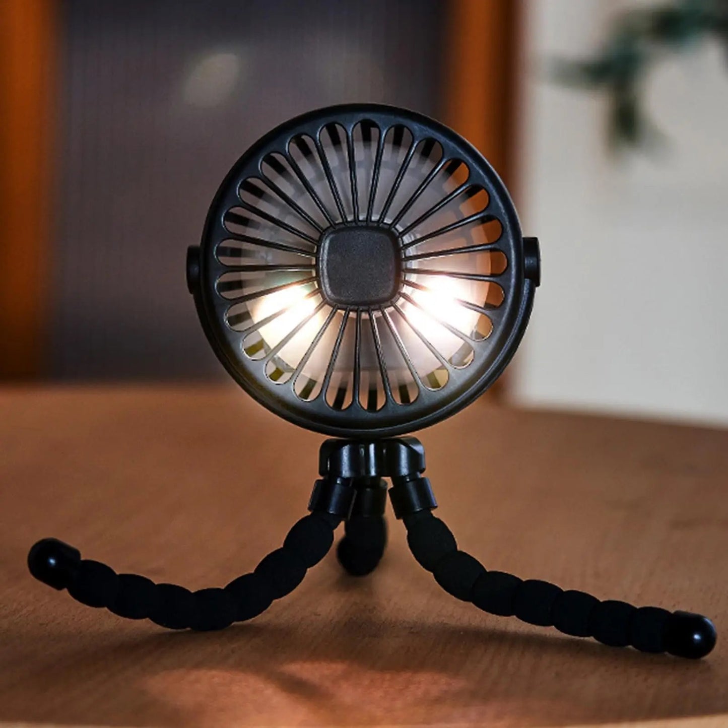 Portable stroller fan with built-in light turned on, standing on flexible legs.